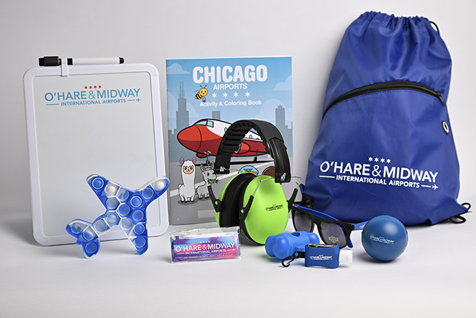 Photo of items found in the sensory bag includes white board and marker, activity book, tote bag, sunglasses, noise canceling headphones and squeezable stress ball.
